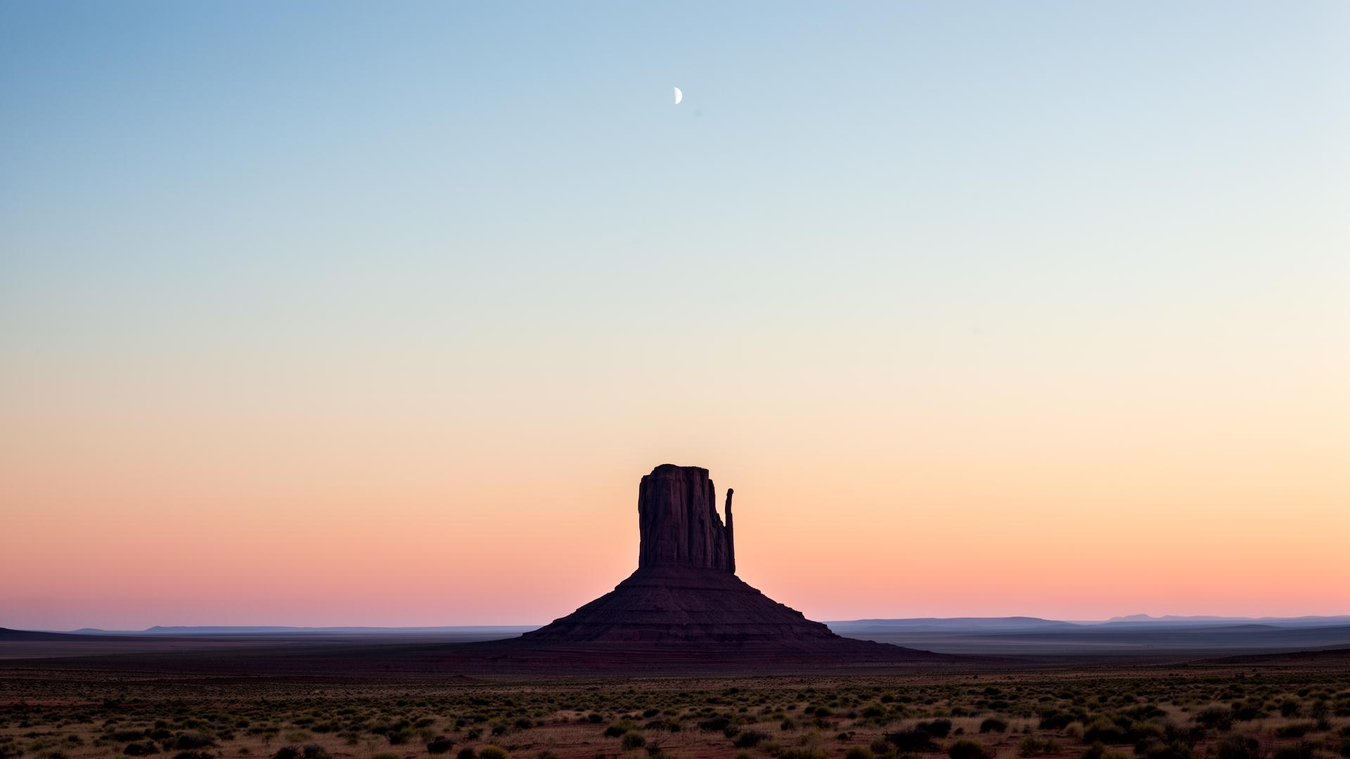 A dramatic rock butte at dawn beneath a soft pastel sky